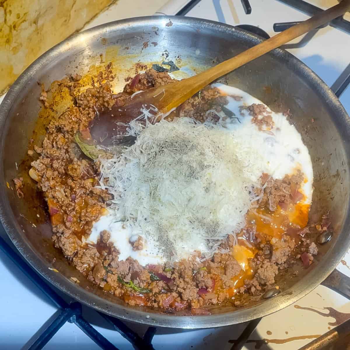 Adding cream and cheese to the ground beef sauce.