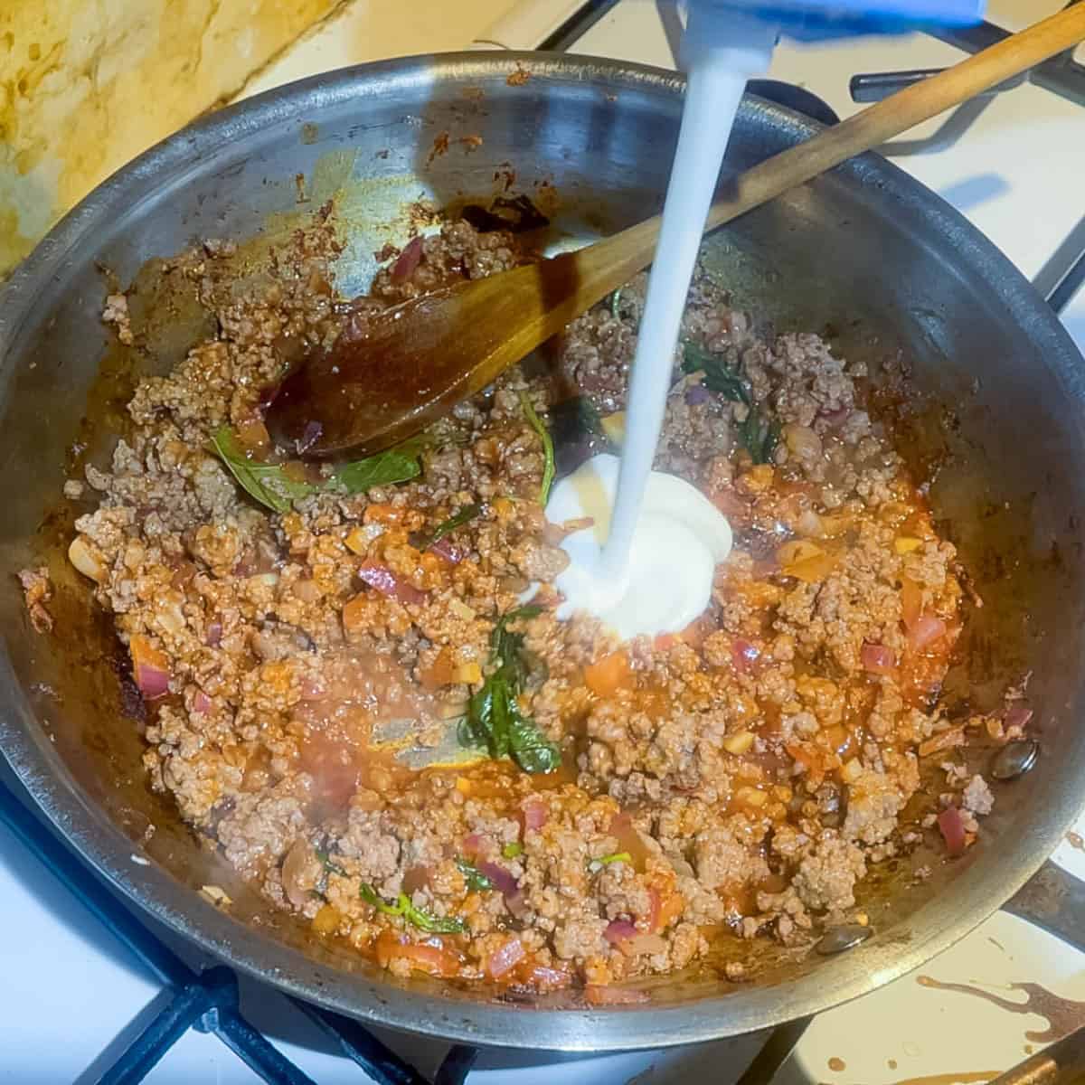 Adding heavy cream to the ground beef sauce.