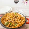 Ground beef with penne pasta in a pan.