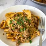 A white plate with ground beef and pasta.
