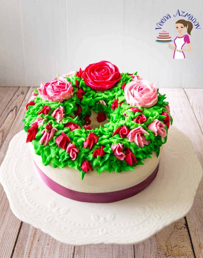 A cake decorated with flowers made with Korean buttercream frosting on a cake stand.