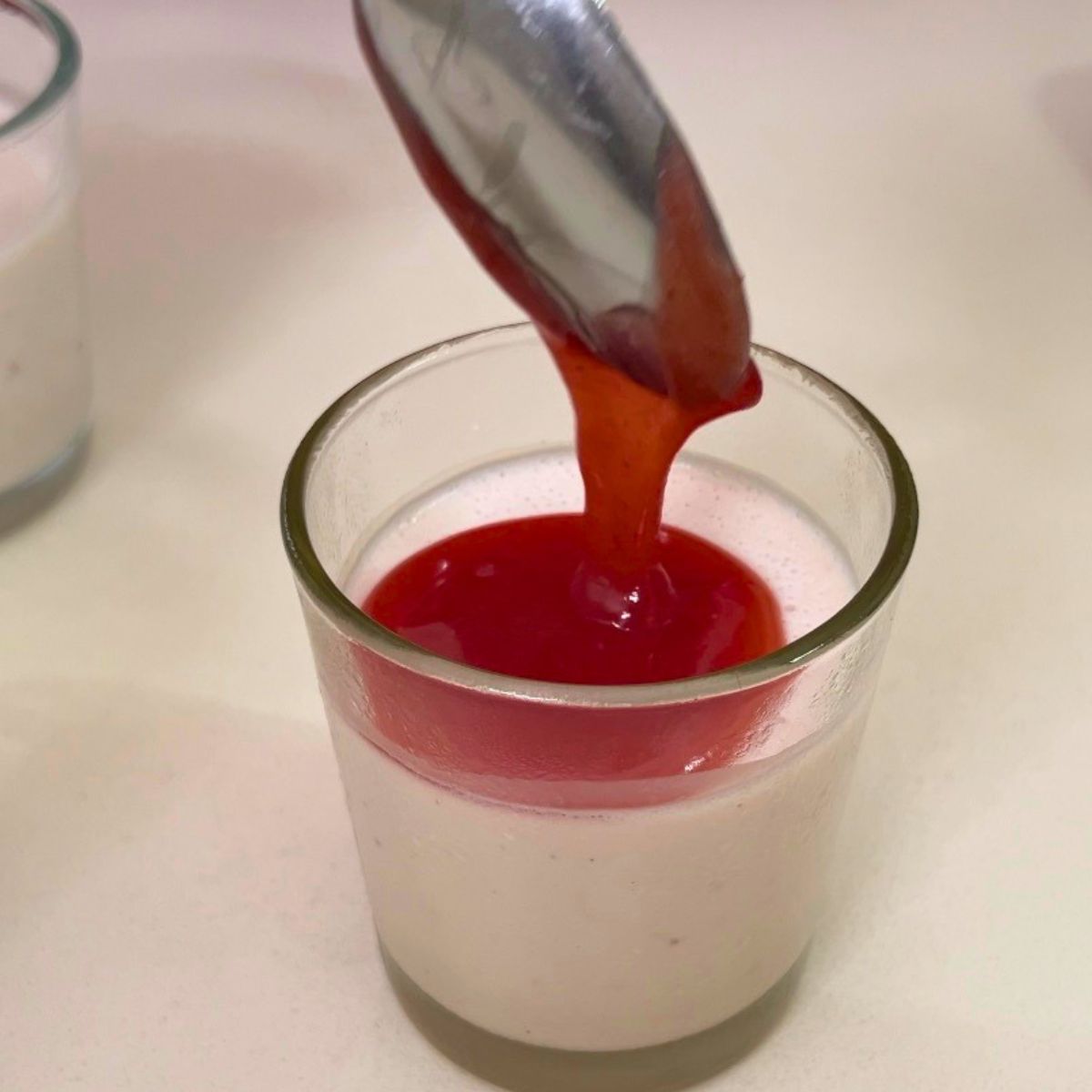 Adding strawberry sauce to the panna cotta.