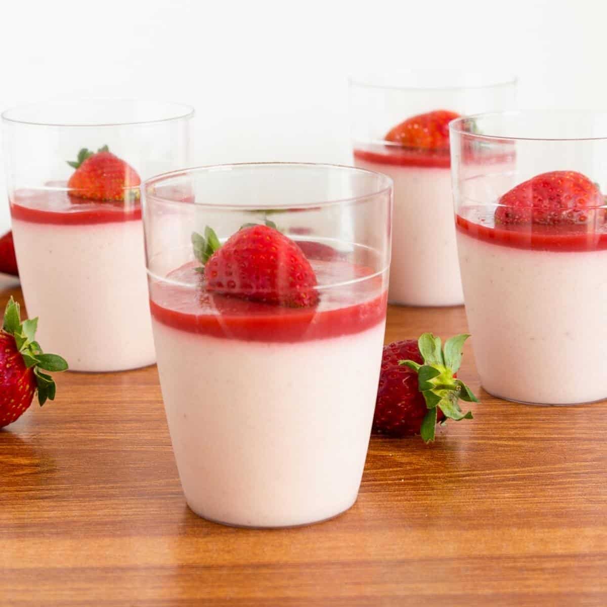 Desserts cups with panna cotta and strawberries.