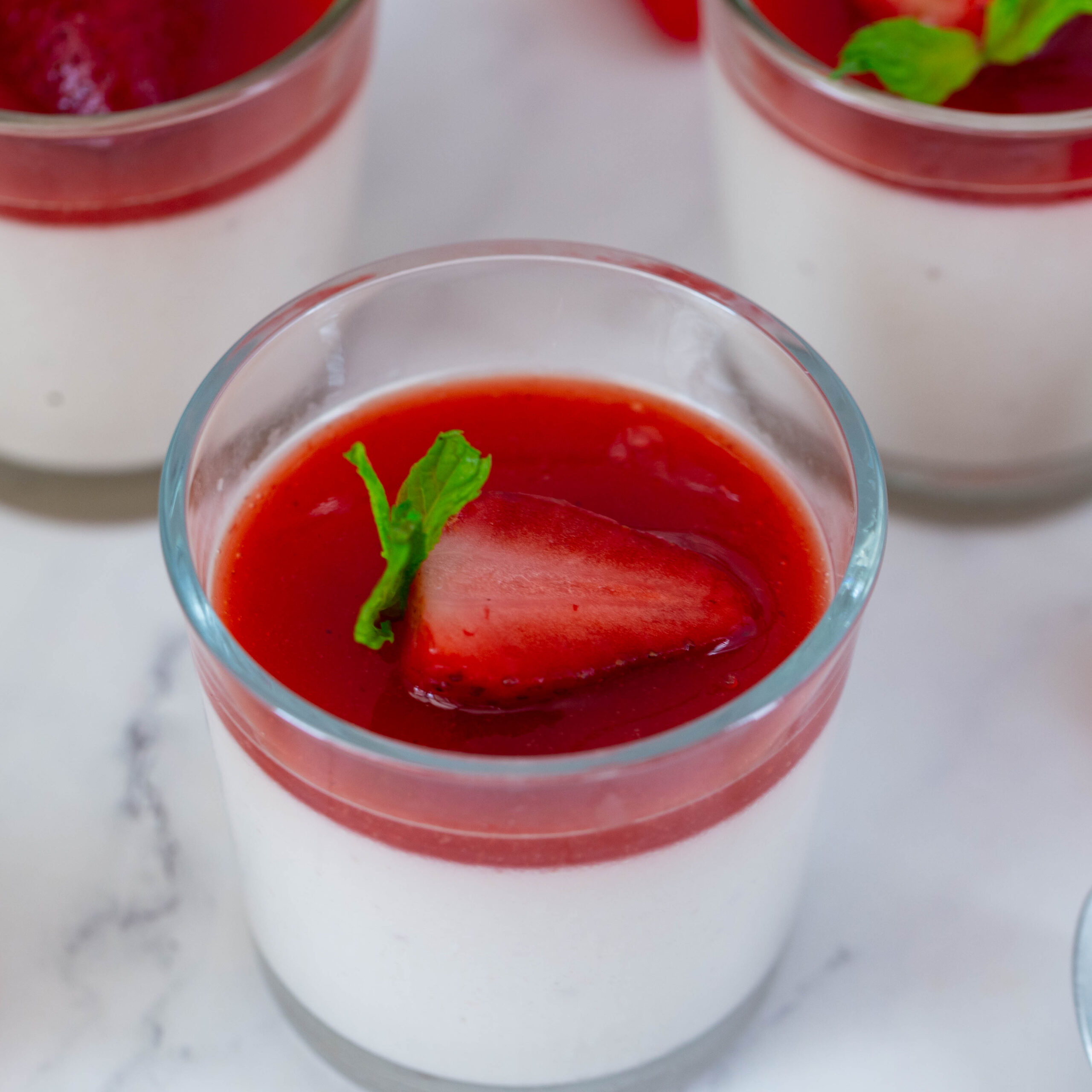 A cup with panna cotta and fresh strawberry sauce.