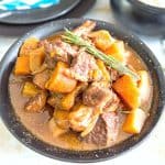A black bowl with crockpot stew.