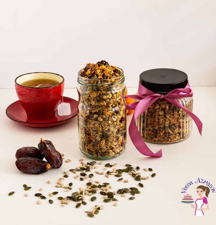 Granola in a jar next to a cup of tea.