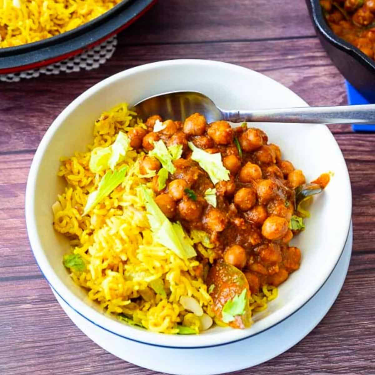 A bowl with yellow rice and channa masala.