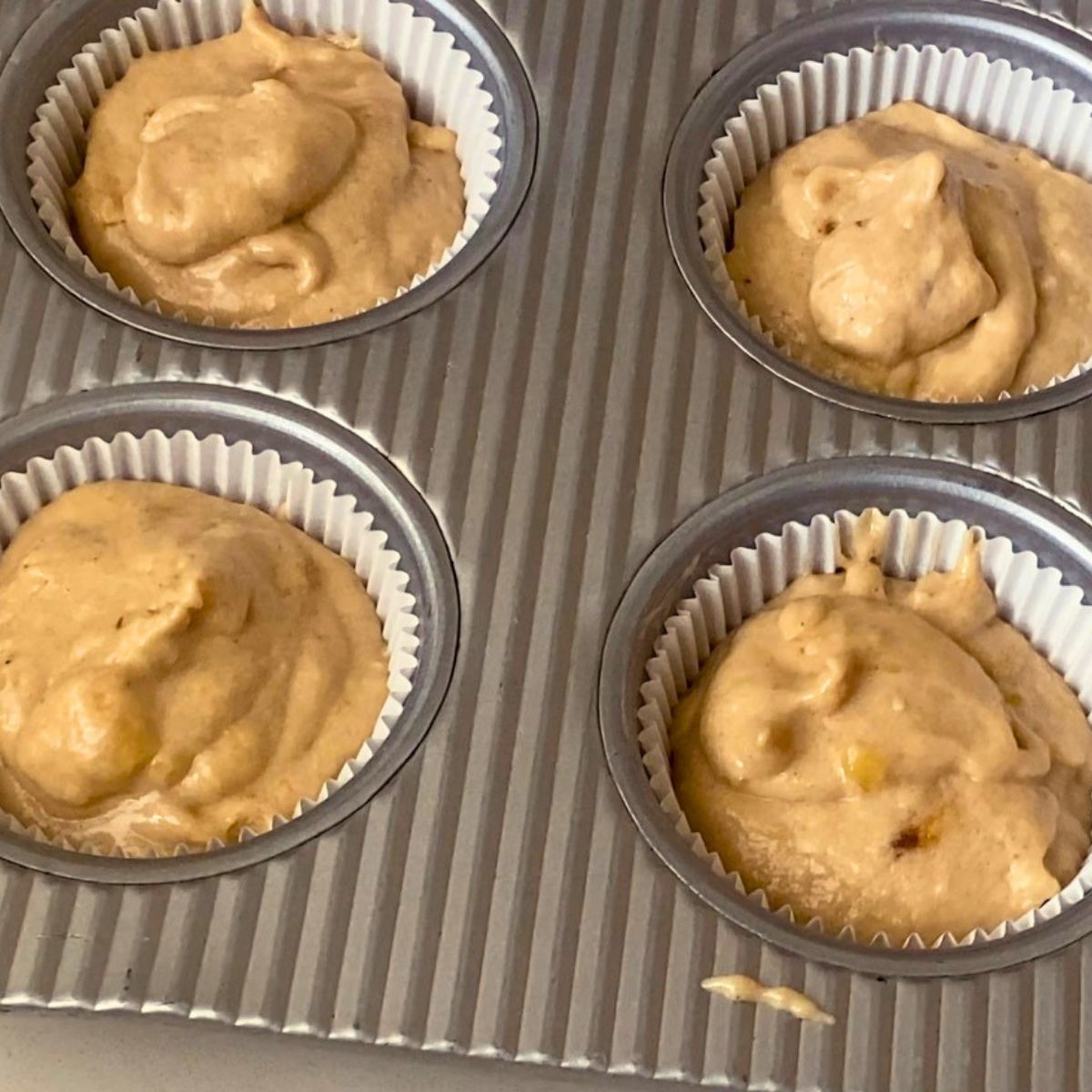 A muffin pan with banana cupcake liners ready for baking.