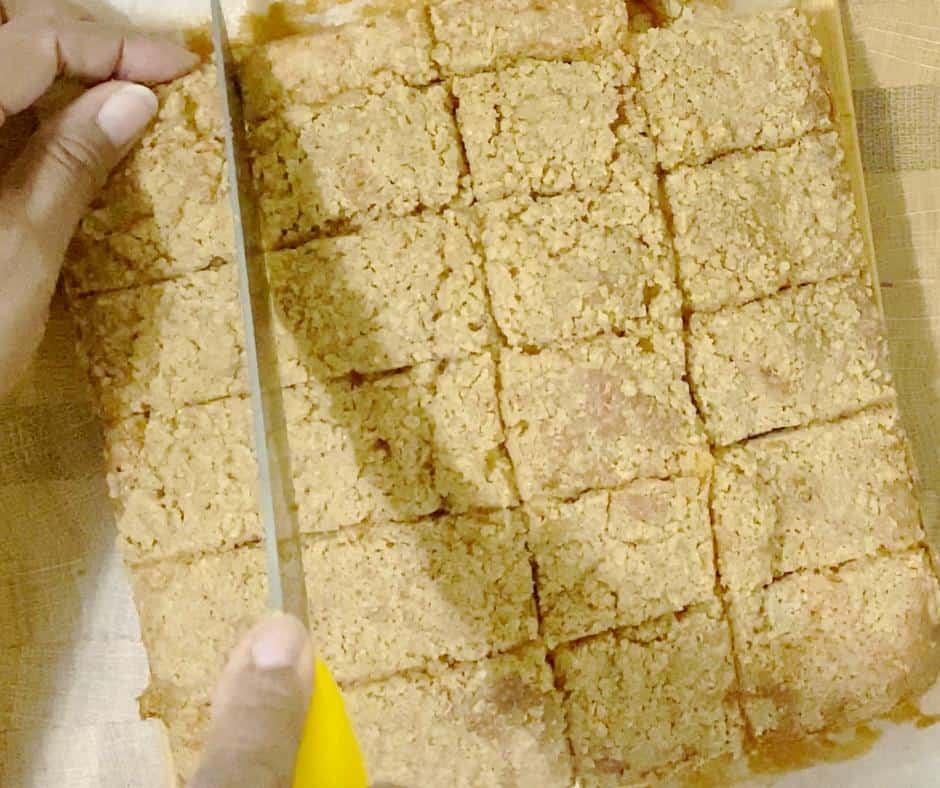 A person slicing a coffee cake in to squares.