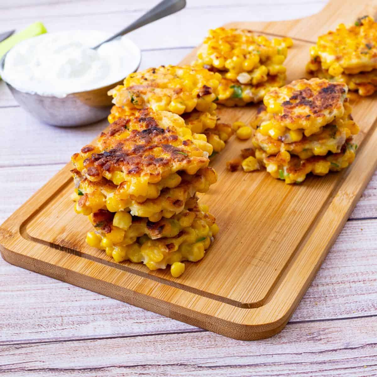 A stack of corn fritters on a wooden board.