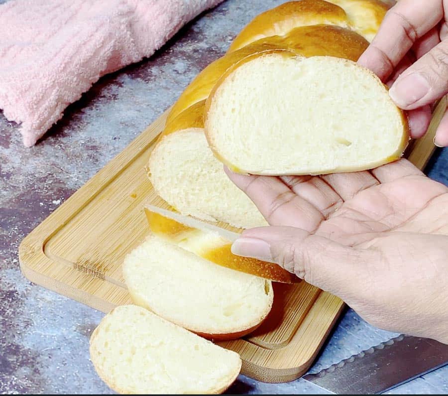 A person holding a slice of challah bread.