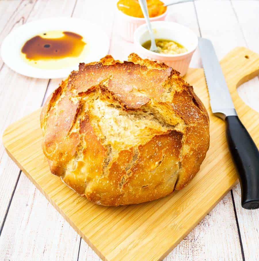 A crusty loaf of bread on a wooden cutting board.