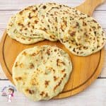 Potato flatbread stacked on a wooden tray.