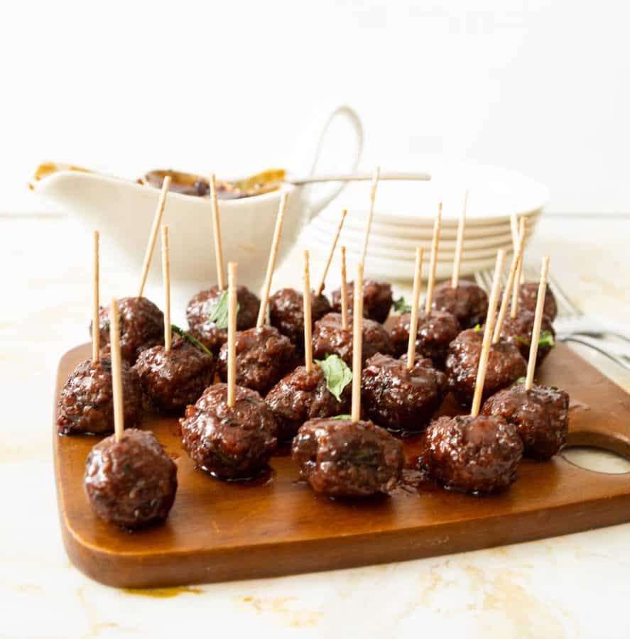 Balsamic glazed meatballs on a wooden tray.