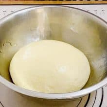 Pizza dough proofing in a bowl.