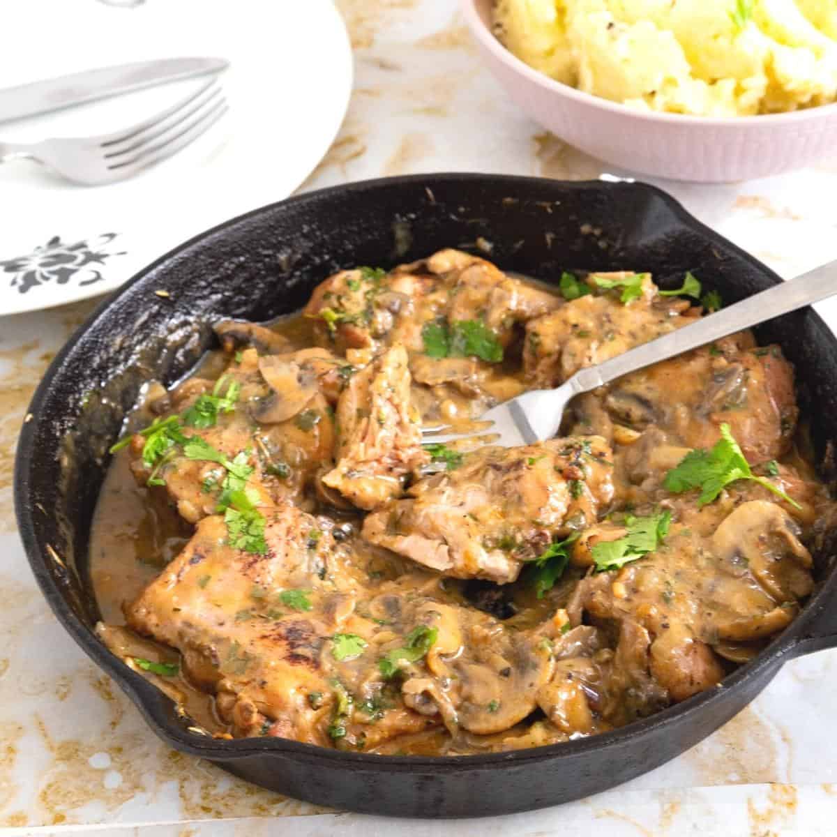 A skillet with chicken with mushrooms sauce.