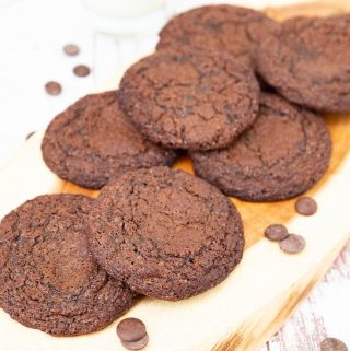 A stack of fudge chocolate cookies on a wooden tray.