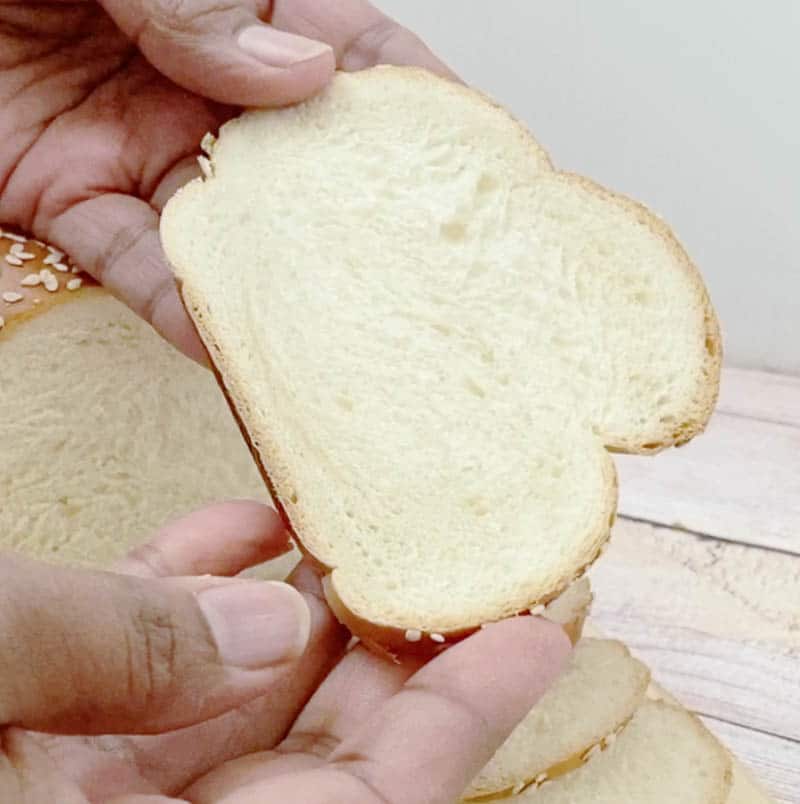 A person holding a slice of challah bread.