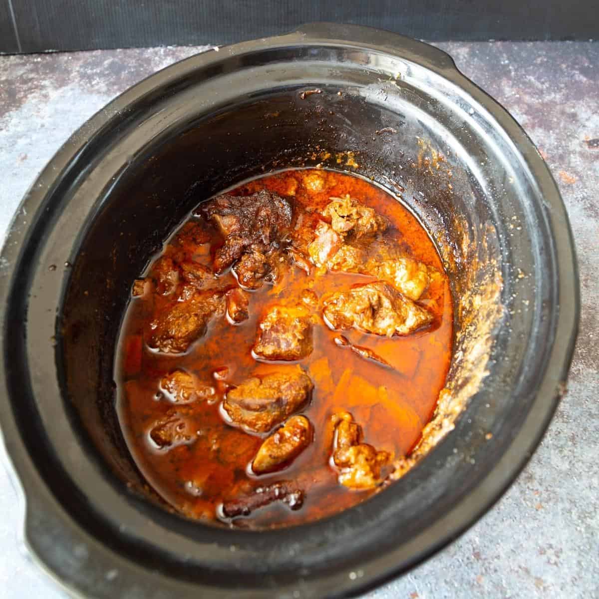 A slow cooker with curry made with goat meat.