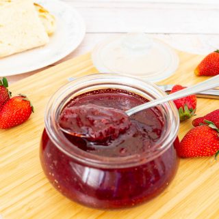 Strawberry jam in a jar with a spoon.