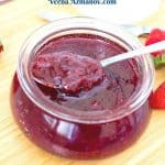 A wooden board with strawberry jam and spoon.