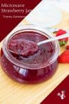Strawberry jam in a jar with a spoon.