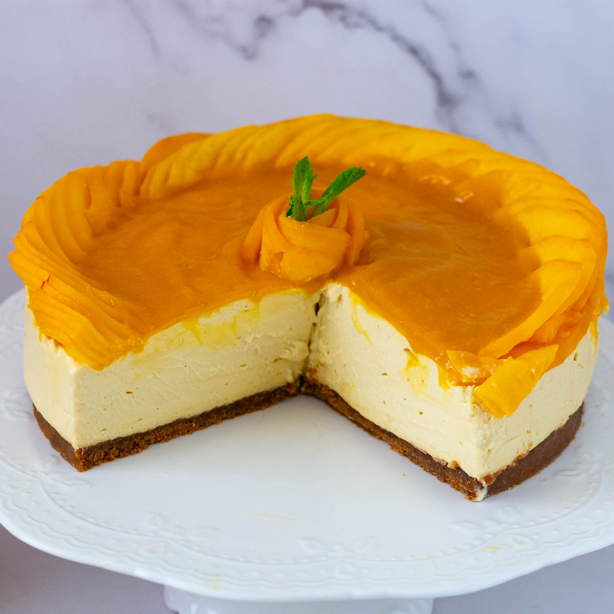A sliced mango cheesecake on the cake stand.