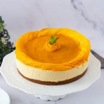 A decorated mango cheesecake on the cake stand.