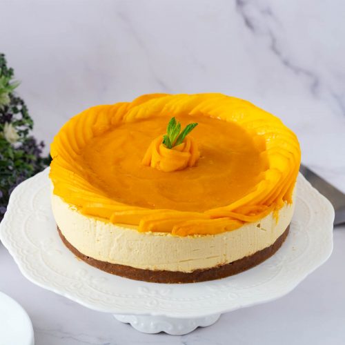 A decorated mango cheesecake on the cake stand.