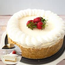 A frosted cheesecake on a cake stand.