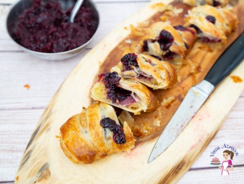 A sliced braided pastry with blackberries on a wooden board.