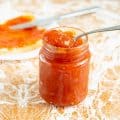 Apricot peach jam in a jar with a spoon.