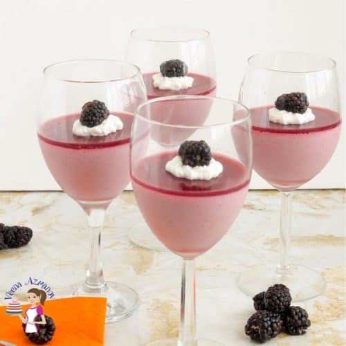 4 wine glasses filled with blackberry Panna Cotta on a table.