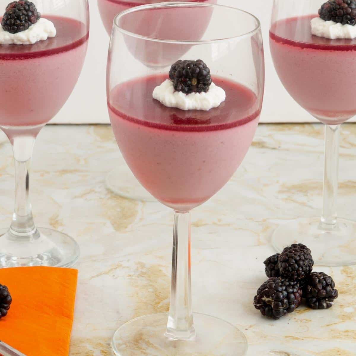 Panna cotta with blackberry jello in wine glasses.