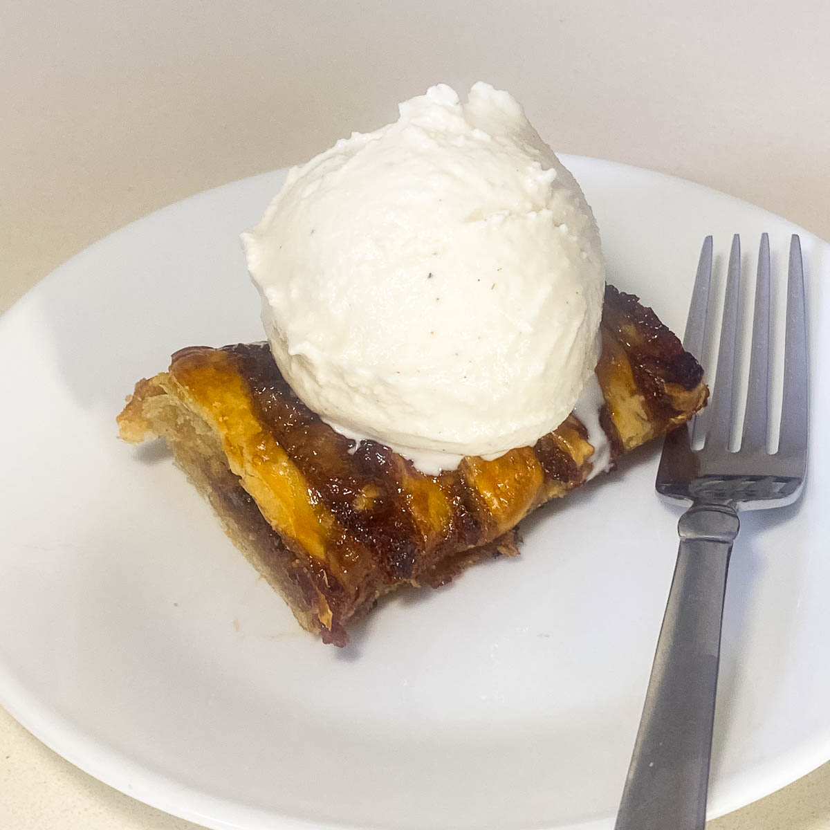 A white plate with braided pastry with ice cream.