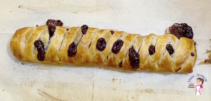 A braided pastry with blackberries on a wooden tray.