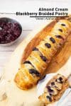 A braided pastry with blackberries on a wooden board.