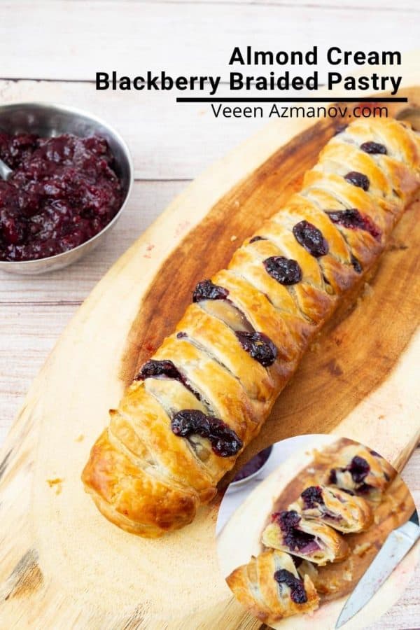 A braided pastry with blackberries on a wooden board.