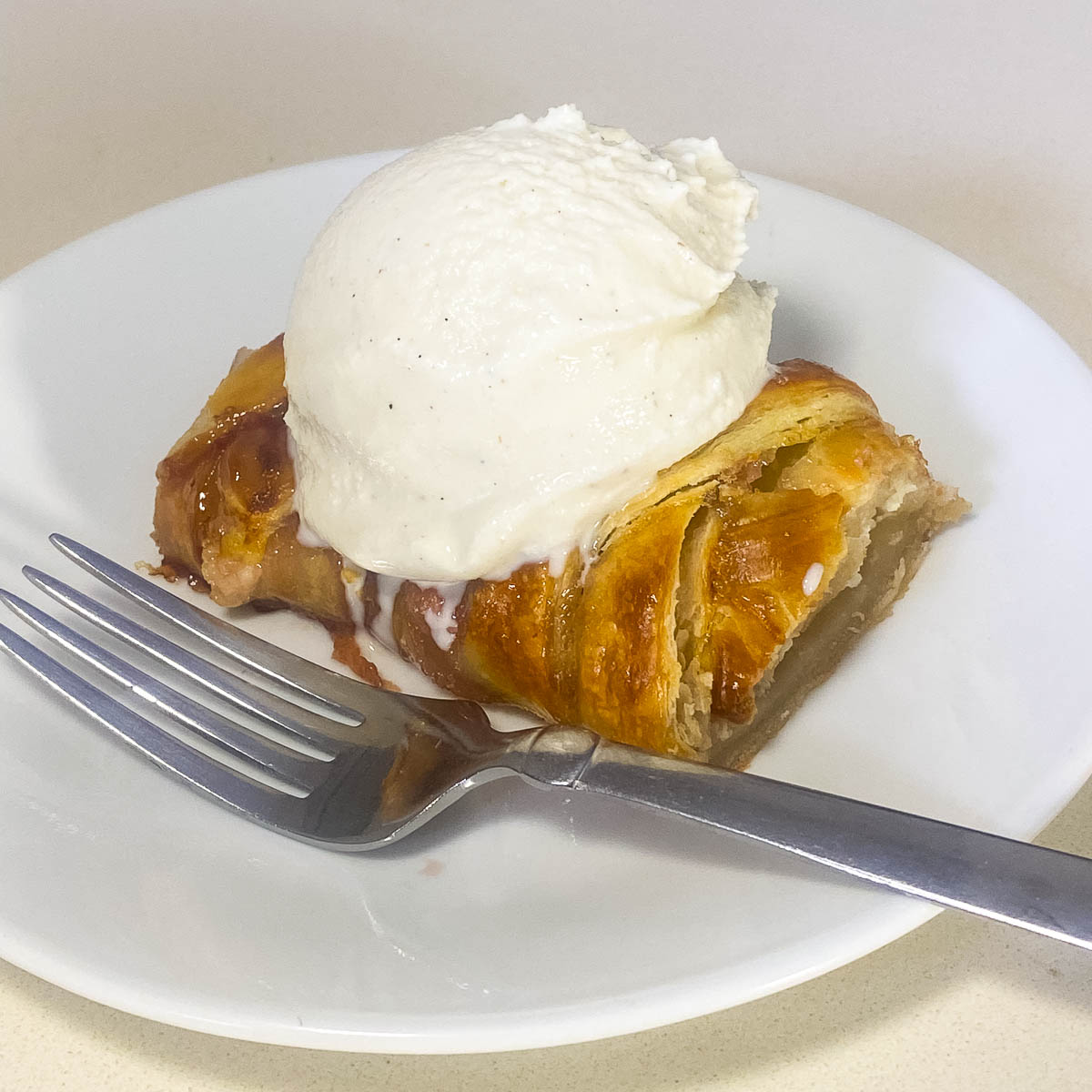 A white plate with braided pastry and ice cream.