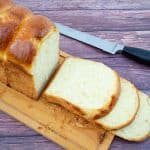 Sliced brioche sandwich bread on a wooden board.