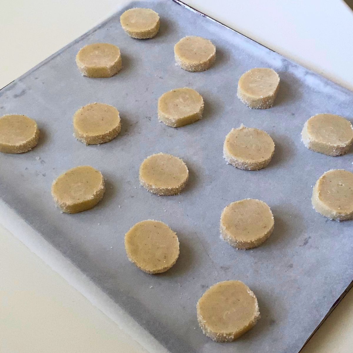 Slice and bake cookies on a baking tray with cardamom.
