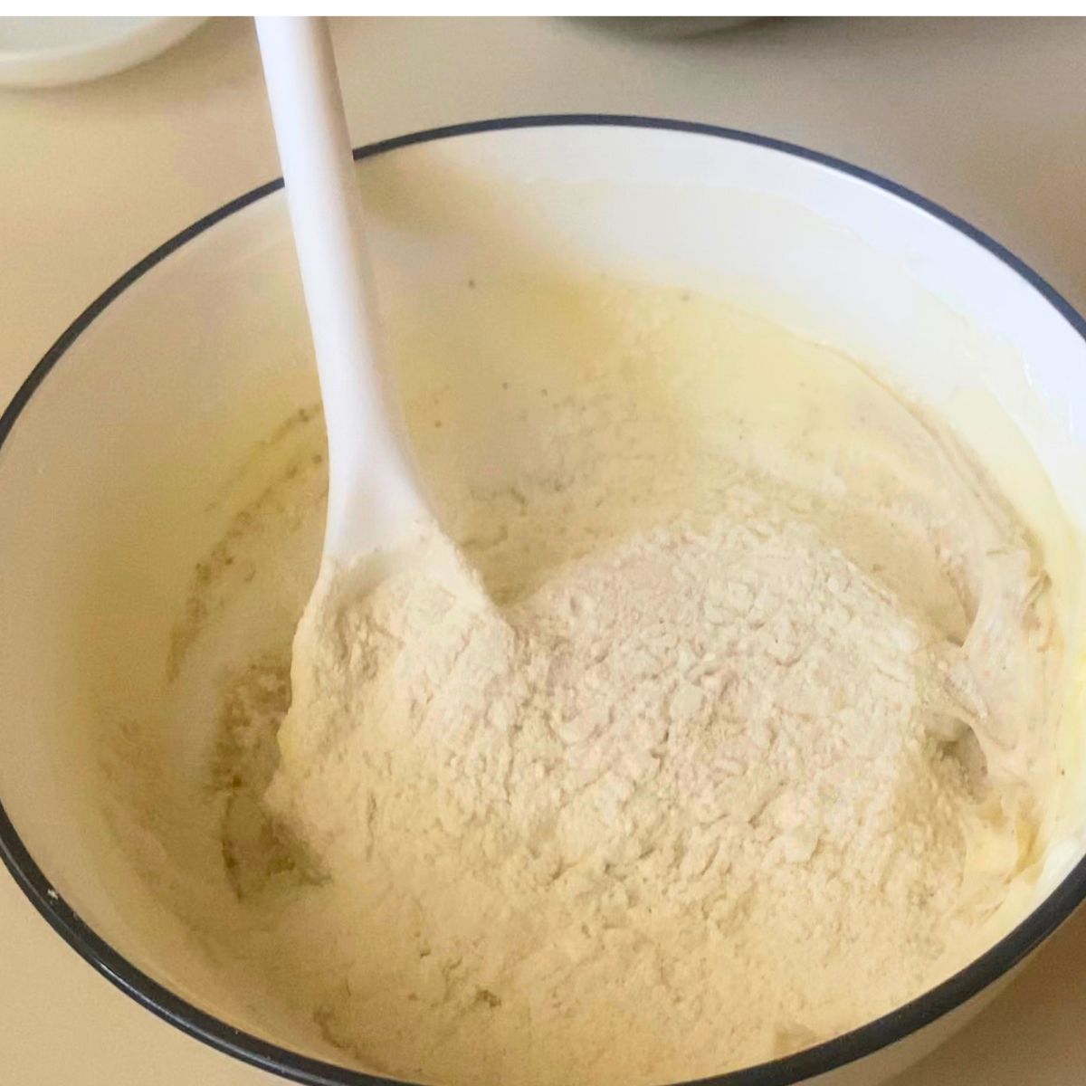 A bowl with all purpose flour to the cookie dough.