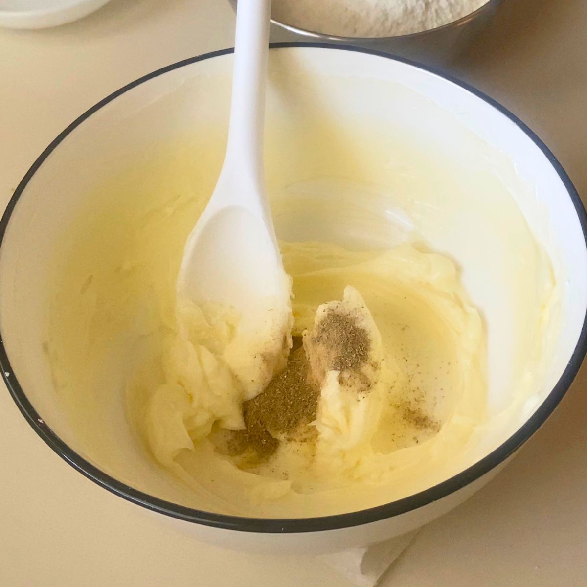 Adding cardamom powder creamed butter and powdered sugar.