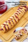 A braided puff pastry with strawberries on a cutting board.