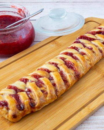 Strawberry braided pastry on a wooden cutting board.