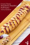 A braided puff pastry with strawberries on a cutting board.