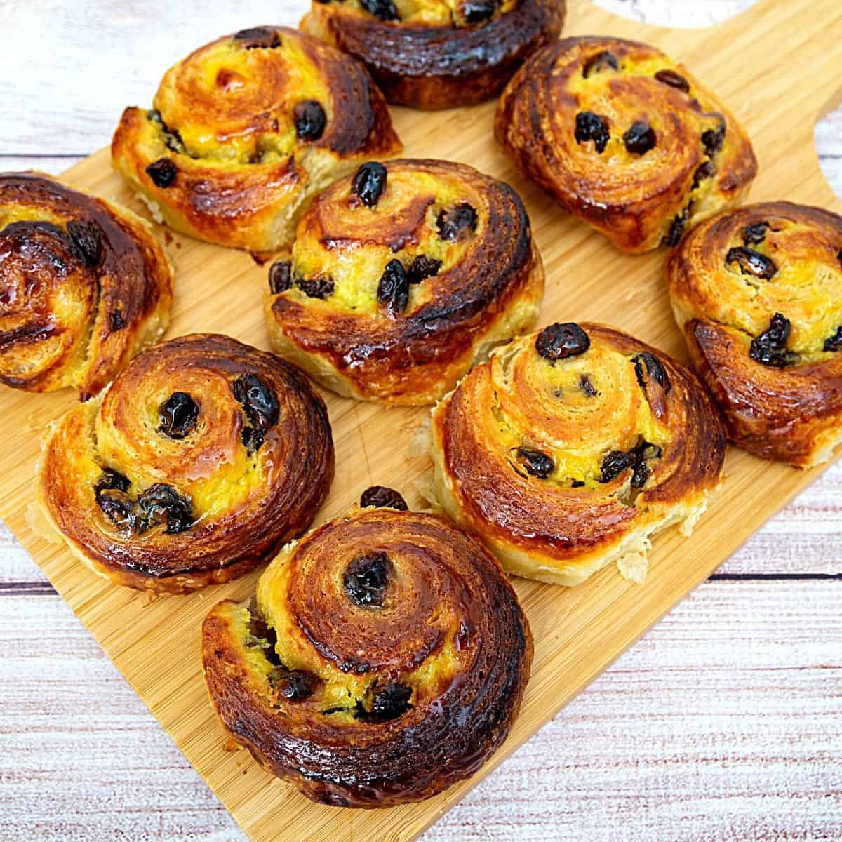 Pain au raisin danishes on a wooden board.
