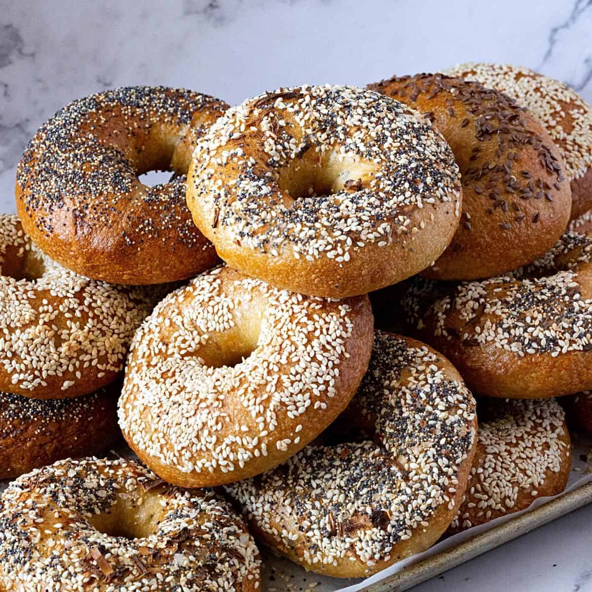 A baking tray with a stack of various bagels.