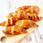 A stack of croissants on a wooden tray.