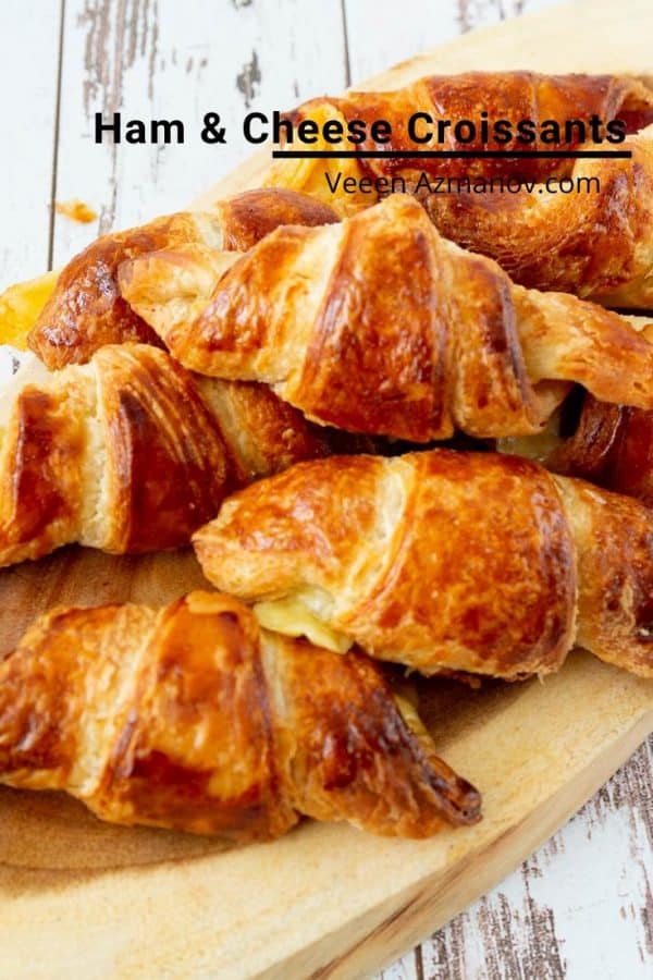 A close up of a stack of croissants on a wooden tray.